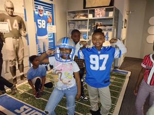 students posing in Lions gear in front of Lions exhibit